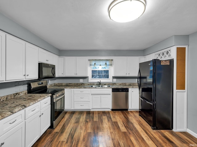 kitchen with dark wood-type flooring, stone counters, black appliances, white cabinets, and sink