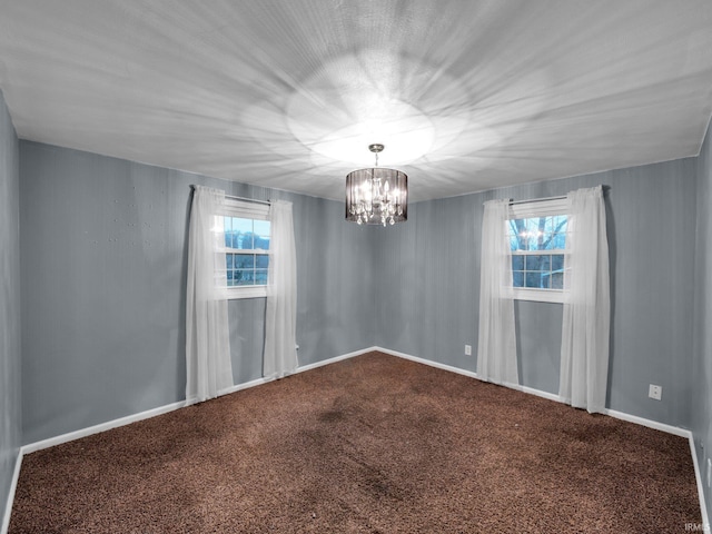 carpeted spare room featuring a chandelier and a healthy amount of sunlight