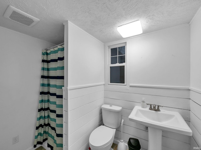 bathroom featuring a shower with shower curtain, a textured ceiling, and toilet