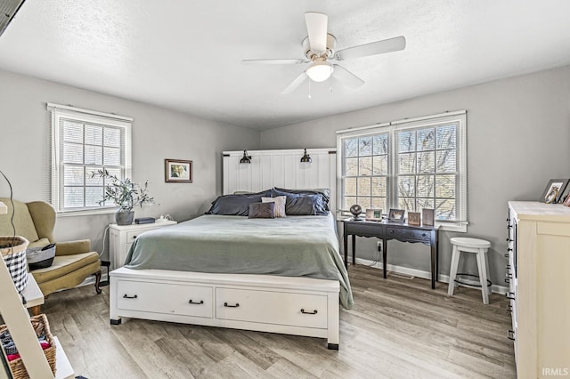 bedroom with ceiling fan, light hardwood / wood-style flooring, and a textured ceiling