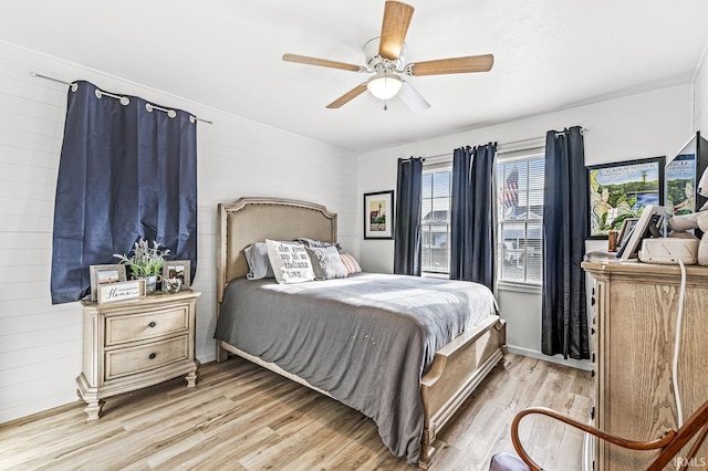 bedroom featuring light wood-type flooring, ceiling fan, and wood walls