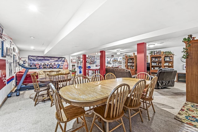 dining space featuring light carpet, indoor bar, and ceiling fan