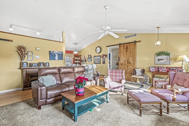 carpeted living room with a barn door, track lighting, ceiling fan, and lofted ceiling