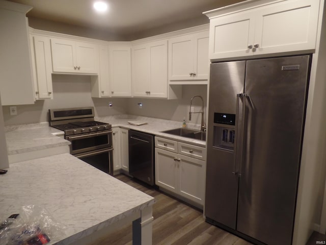 kitchen featuring appliances with stainless steel finishes, dark hardwood / wood-style flooring, white cabinetry, and sink