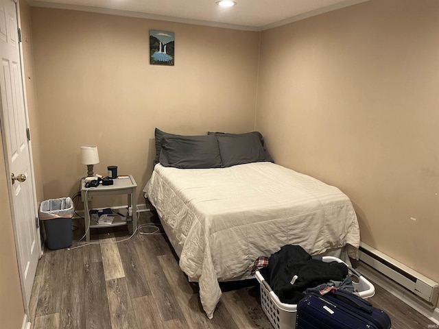 bedroom with crown molding, dark wood-type flooring, and a baseboard heating unit