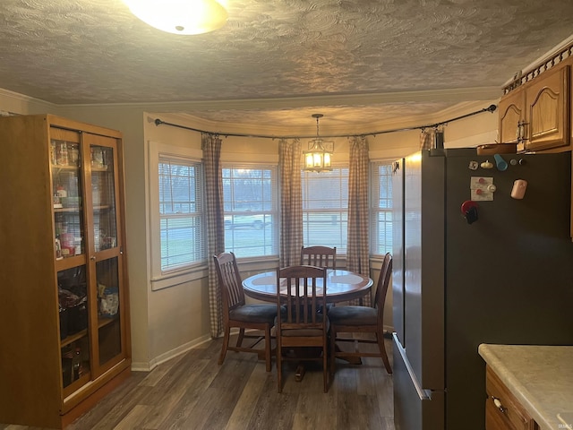 dining space featuring ornamental molding, a textured ceiling, an inviting chandelier, and dark wood-type flooring