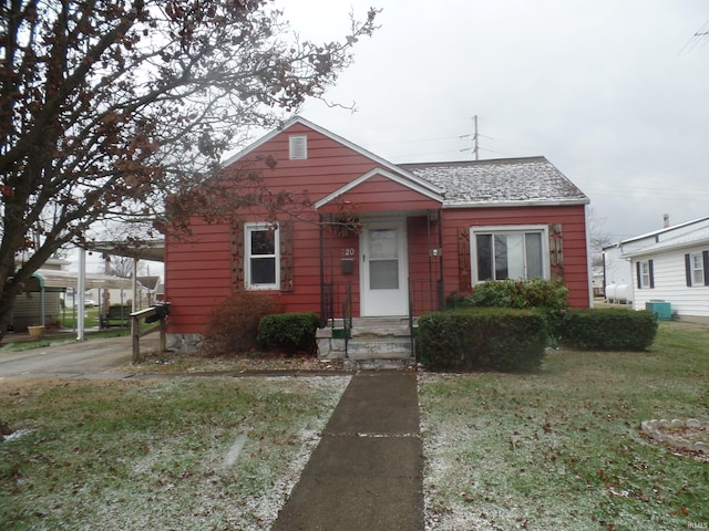 bungalow featuring a carport, cooling unit, and a front lawn