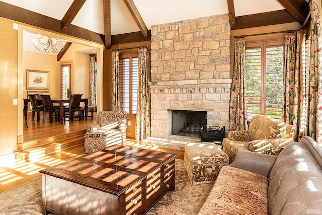 living room featuring vaulted ceiling with beams, hardwood / wood-style floors, a stone fireplace, and a notable chandelier