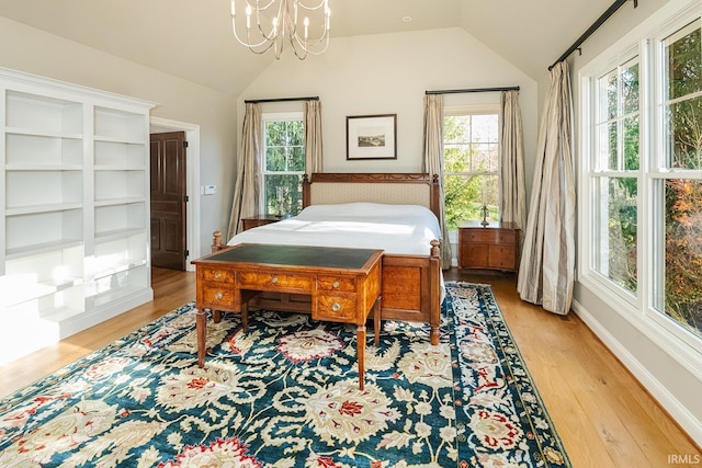 bedroom featuring light hardwood / wood-style floors, lofted ceiling, and a notable chandelier