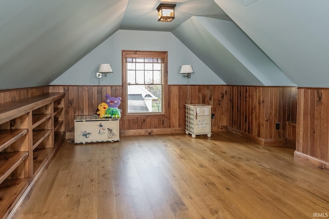 bonus room featuring wood walls, lofted ceiling, and hardwood / wood-style flooring