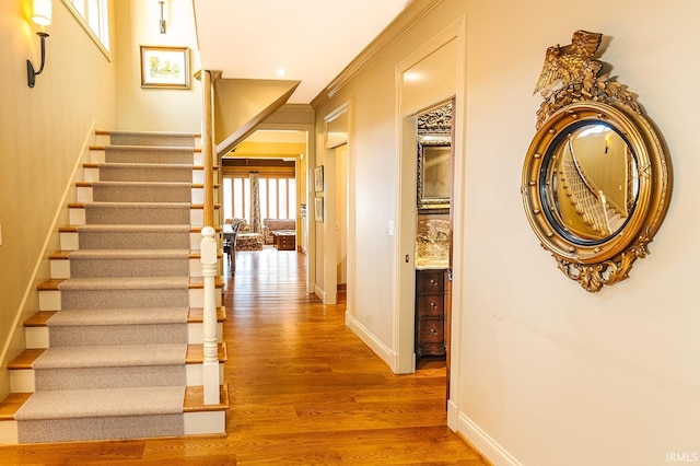 stairs with crown molding and hardwood / wood-style flooring