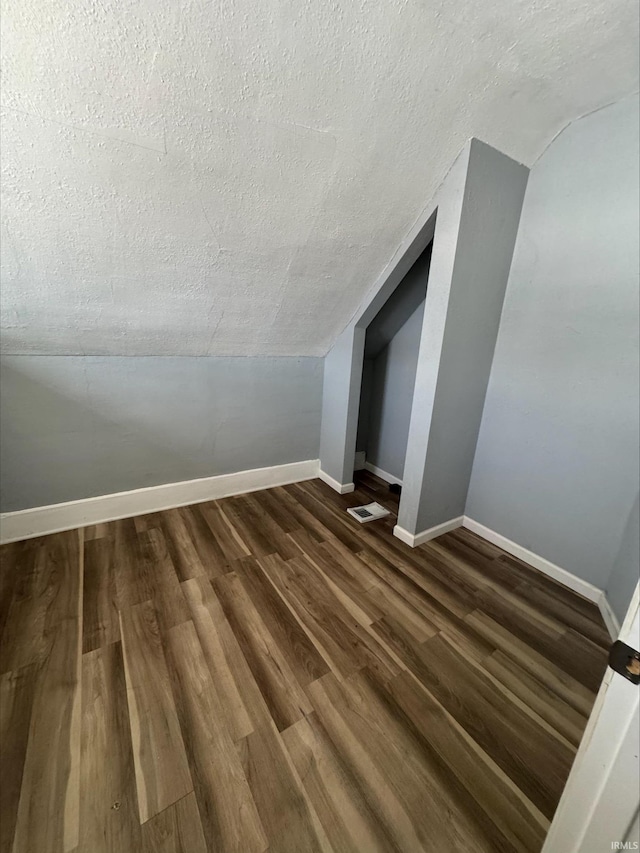 bonus room featuring dark hardwood / wood-style flooring, lofted ceiling, and a textured ceiling