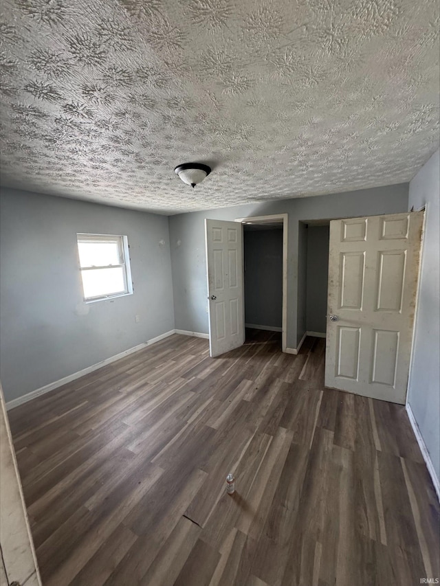 unfurnished bedroom featuring a textured ceiling and dark hardwood / wood-style floors