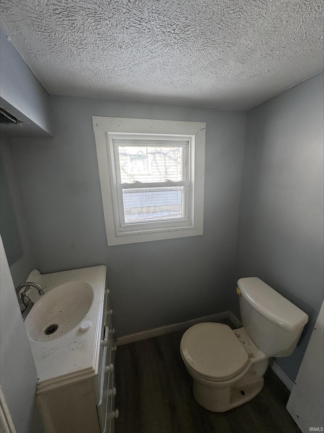 bathroom with hardwood / wood-style floors, vanity, toilet, and a textured ceiling