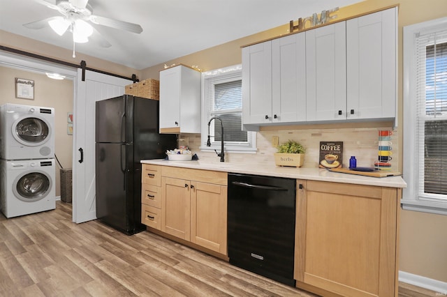 kitchen featuring black appliances, white cabinets, light hardwood / wood-style flooring, decorative backsplash, and a barn door