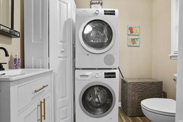 washroom featuring sink, stacked washer and clothes dryer, and hardwood / wood-style flooring