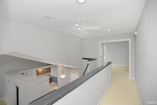 corridor featuring light colored carpet and a textured ceiling