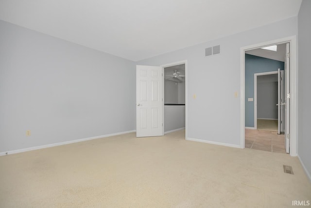 unfurnished bedroom with a walk in closet, light carpet, and a closet