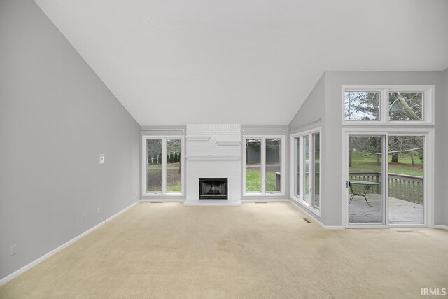 unfurnished living room featuring light colored carpet, high vaulted ceiling, and a brick fireplace