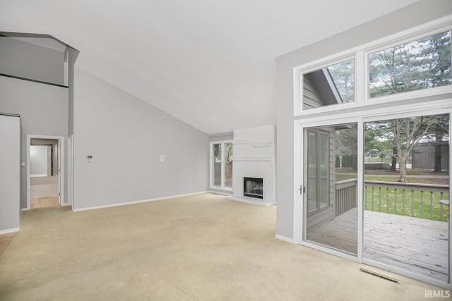 unfurnished living room featuring a large fireplace, high vaulted ceiling, and light colored carpet