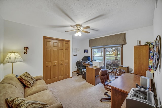 carpeted home office with ceiling fan and a textured ceiling