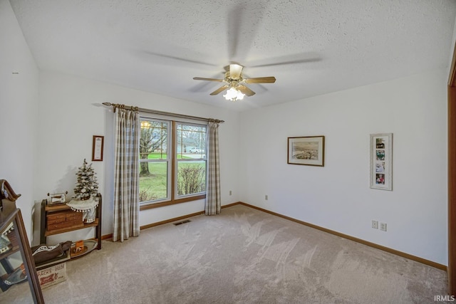 empty room with light carpet, ceiling fan, and a textured ceiling