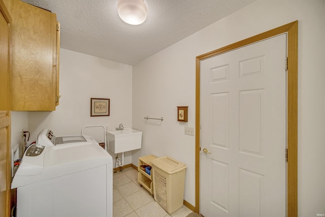 washroom with cabinets, sink, separate washer and dryer, a textured ceiling, and light tile patterned floors