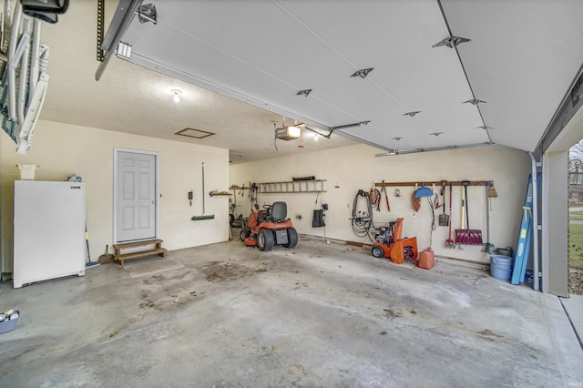 garage with a garage door opener and white refrigerator