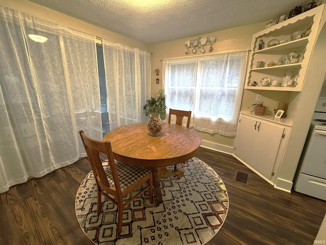 dining room featuring a textured ceiling and dark hardwood / wood-style floors