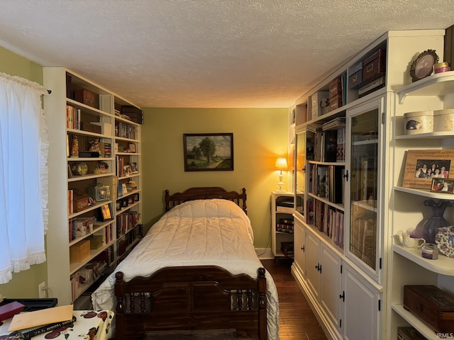 bedroom featuring a textured ceiling and dark hardwood / wood-style flooring