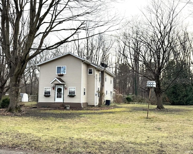 view of front of house with cooling unit and a front lawn