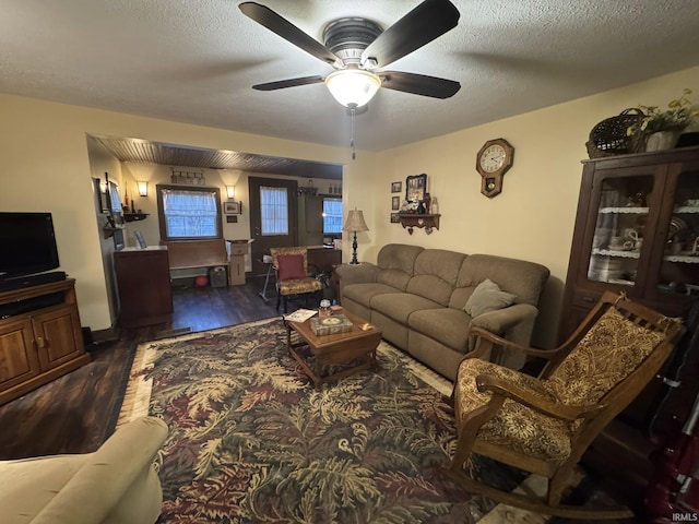 living room featuring ceiling fan, dark hardwood / wood-style flooring, and a textured ceiling