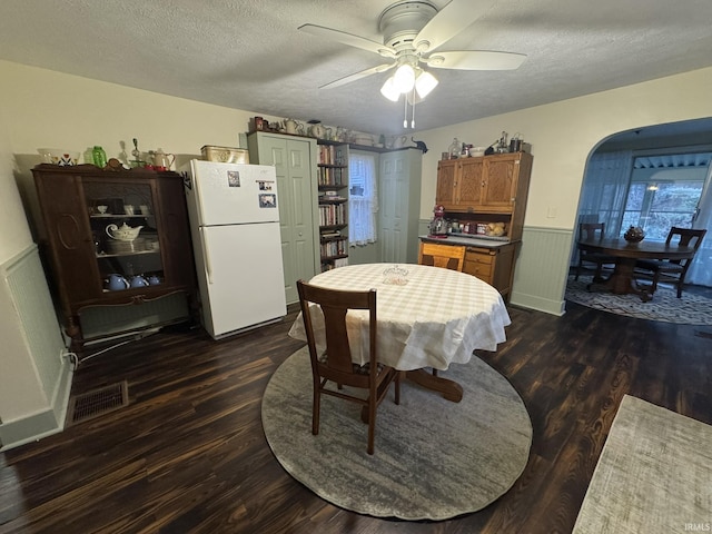 dining room featuring a textured ceiling, dark hardwood / wood-style flooring, and ceiling fan