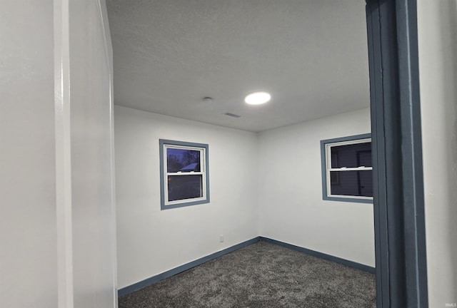 carpeted empty room featuring a textured ceiling