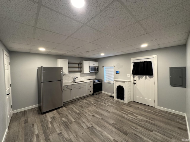 kitchen with appliances with stainless steel finishes, sink, hardwood / wood-style flooring, white cabinets, and electric panel