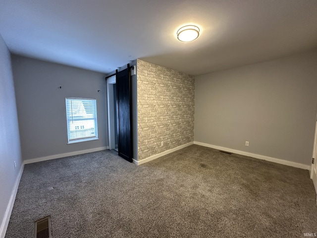 spare room featuring dark colored carpet and a barn door