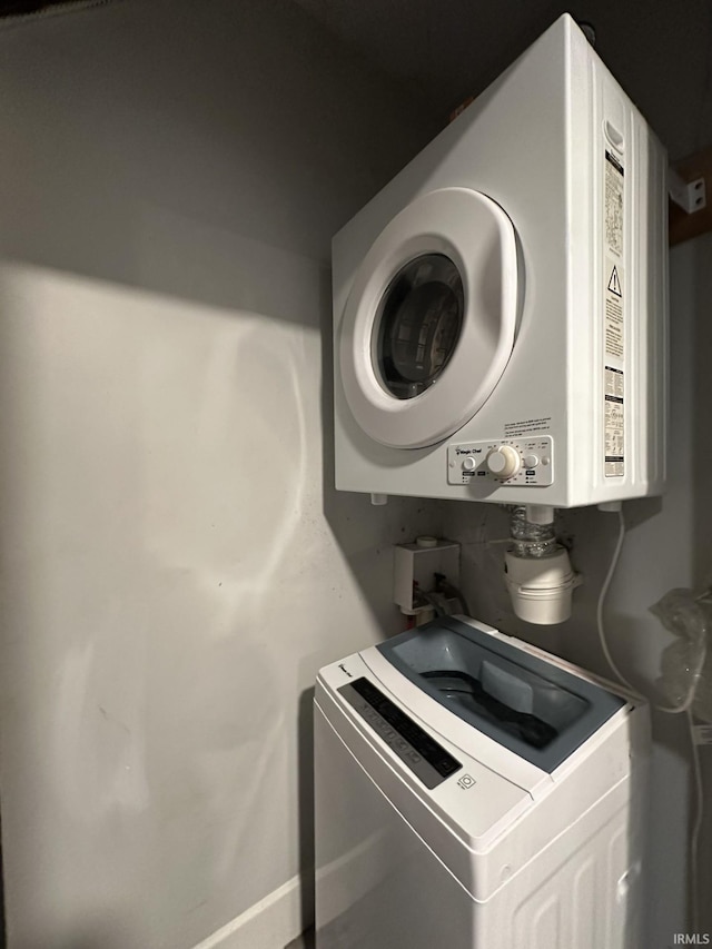 laundry area featuring stacked washer and dryer and tankless water heater