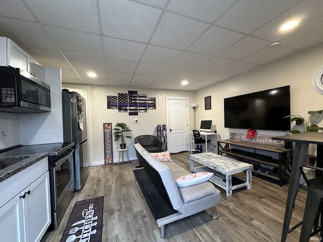 living room with wood-type flooring and a paneled ceiling