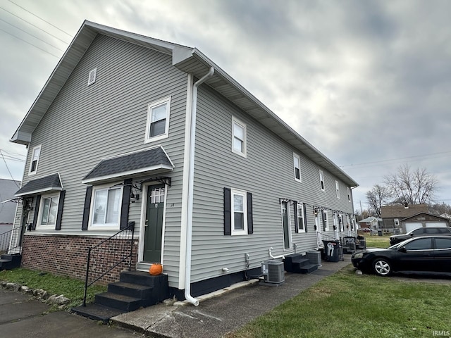 view of side of home with a yard and central air condition unit