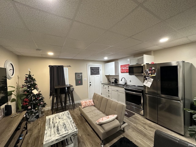 kitchen featuring appliances with stainless steel finishes, tasteful backsplash, sink, wood-type flooring, and white cabinetry