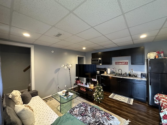 living room featuring dark hardwood / wood-style flooring, a drop ceiling, and sink