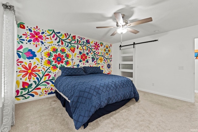 carpeted bedroom featuring ceiling fan and a barn door