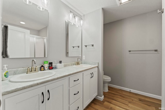 bathroom with hardwood / wood-style floors, vanity, toilet, and an enclosed shower