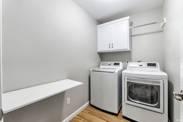 laundry room with washing machine and dryer, cabinets, and light wood-type flooring