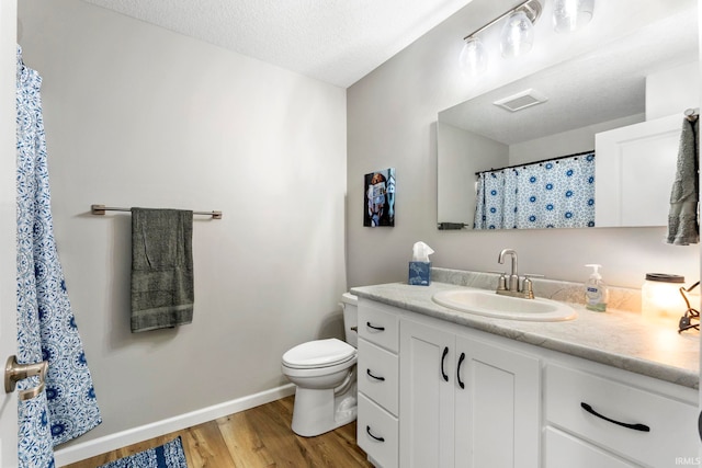 bathroom featuring a textured ceiling, vanity, hardwood / wood-style flooring, and toilet