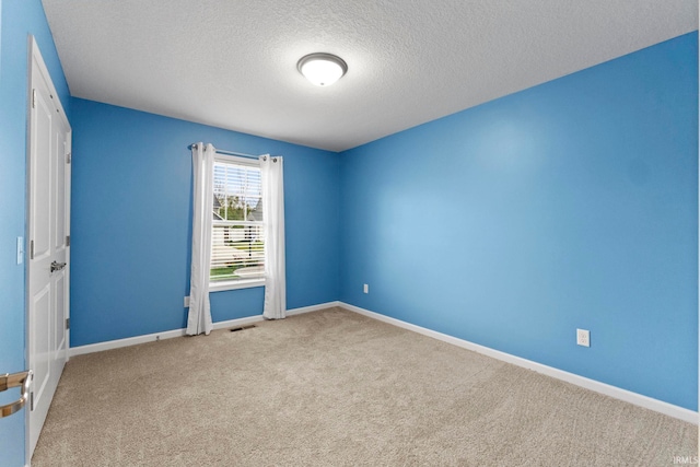 empty room with a textured ceiling and light colored carpet