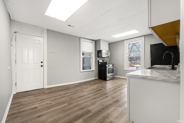 kitchen featuring a drop ceiling, sink, white cabinetry, hardwood / wood-style flooring, and appliances with stainless steel finishes