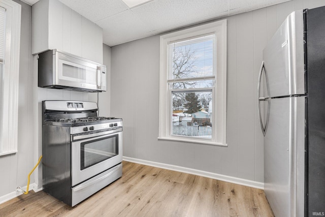 kitchen with light wood-type flooring, a paneled ceiling, and stainless steel appliances