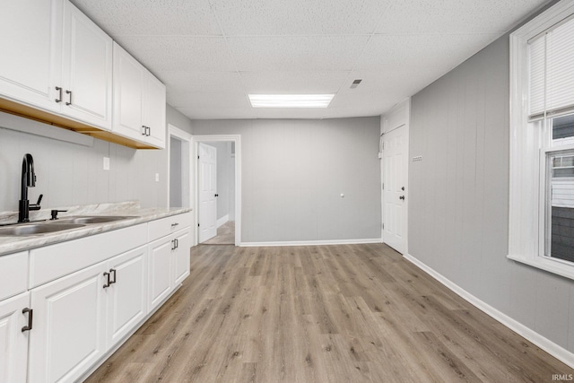 kitchen with white cabinets, light wood-type flooring, and sink