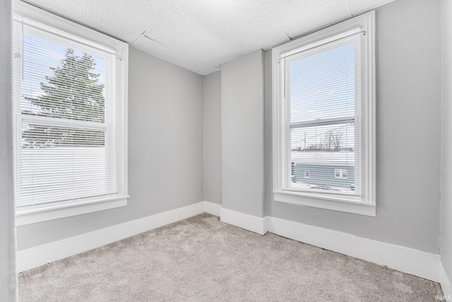 carpeted empty room featuring a paneled ceiling and plenty of natural light